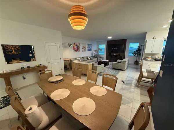 a living room with couches and a dining table with wooden floor