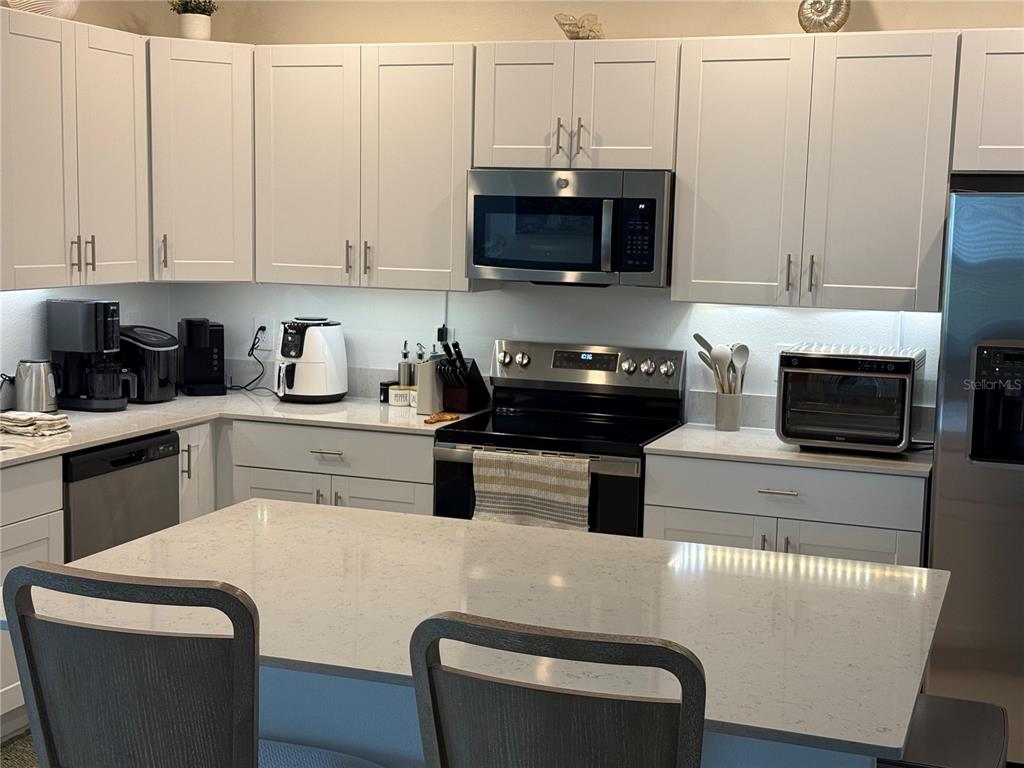 9276 Bonita Mar Drive Parrish, FL 34219 - Photo 38 of 54 a kitchen with stainless steel appliances granite countertop a refrigerator a stove a microwave a sink and white cabinets