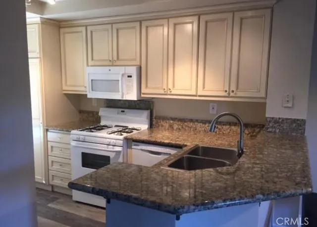 a kitchen with granite countertop a sink stove and cabinets