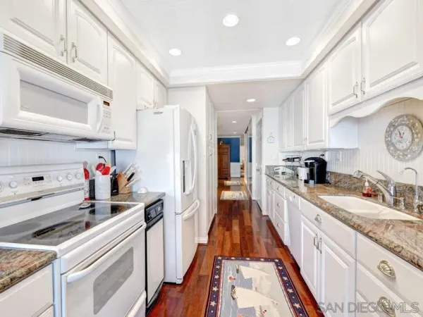 a kitchen with white cabinets and appliances