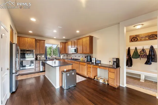 a kitchen with stainless steel appliances a stove top oven a sink a refrigerator white cabinets and wooden floor