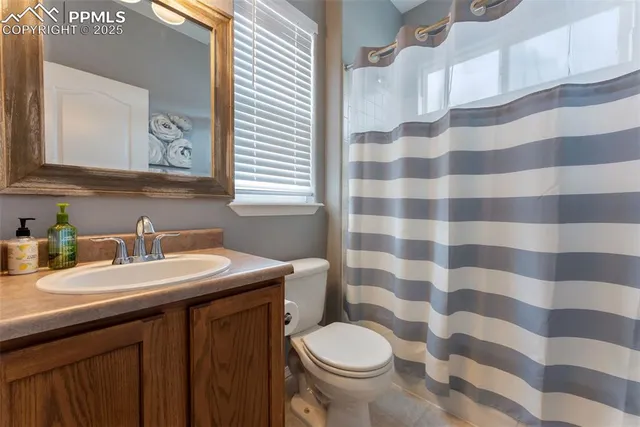 a bathroom with a sink a toilet a mirror and shower curtain