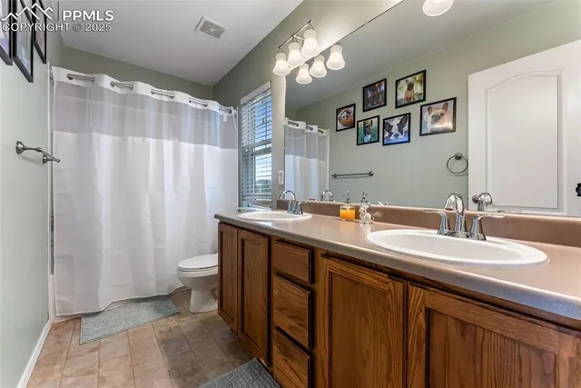 a bathroom with double vanity sink a toilet a mirror and shower