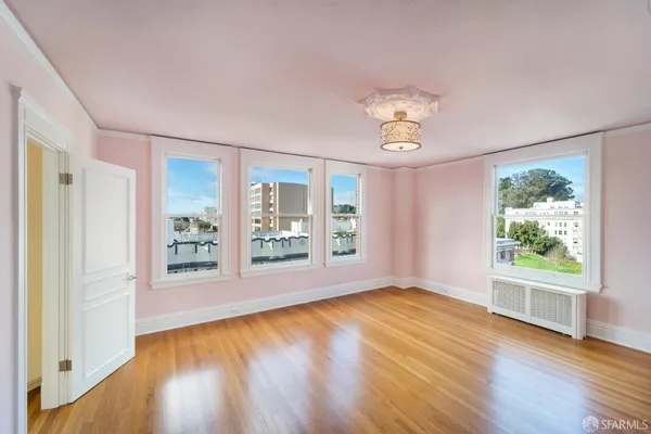 a view of an empty room with a window and wooden floor