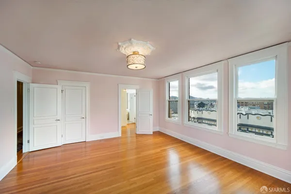 a view of an empty room with a window and wooden floor
