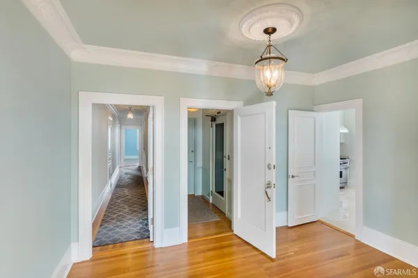 a view of a hallway with wooden floor and a chandelier