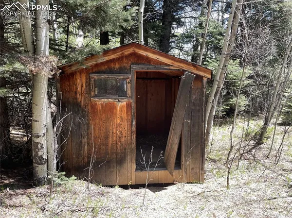 a view of a wooden house with a bench and a tree