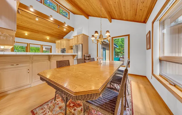 a dining room with stainless steel appliances furniture a window and wooden floor