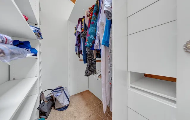 a view of walk in closet with clothes and shoes