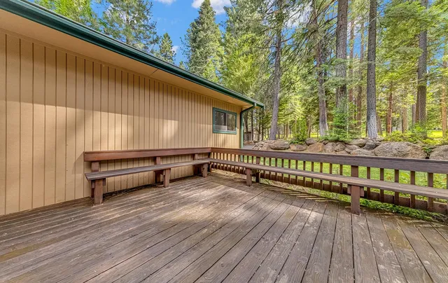 a view of a roof deck with wooden floor and fence and a bench