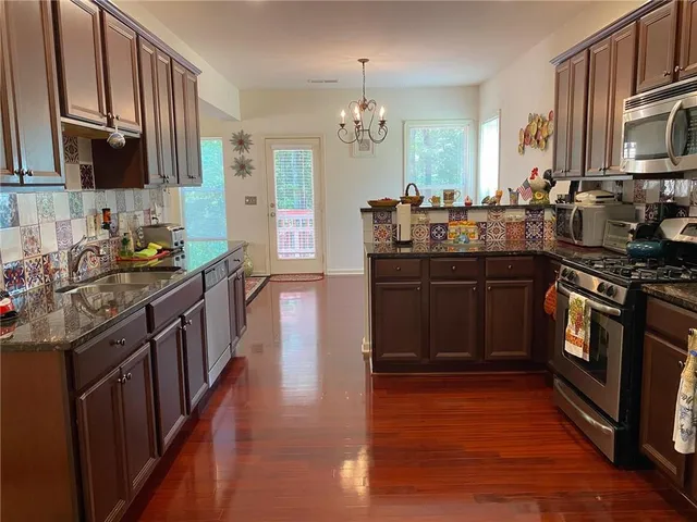 a kitchen with granite countertop a sink dishwasher stove and cabinets with wooden floor