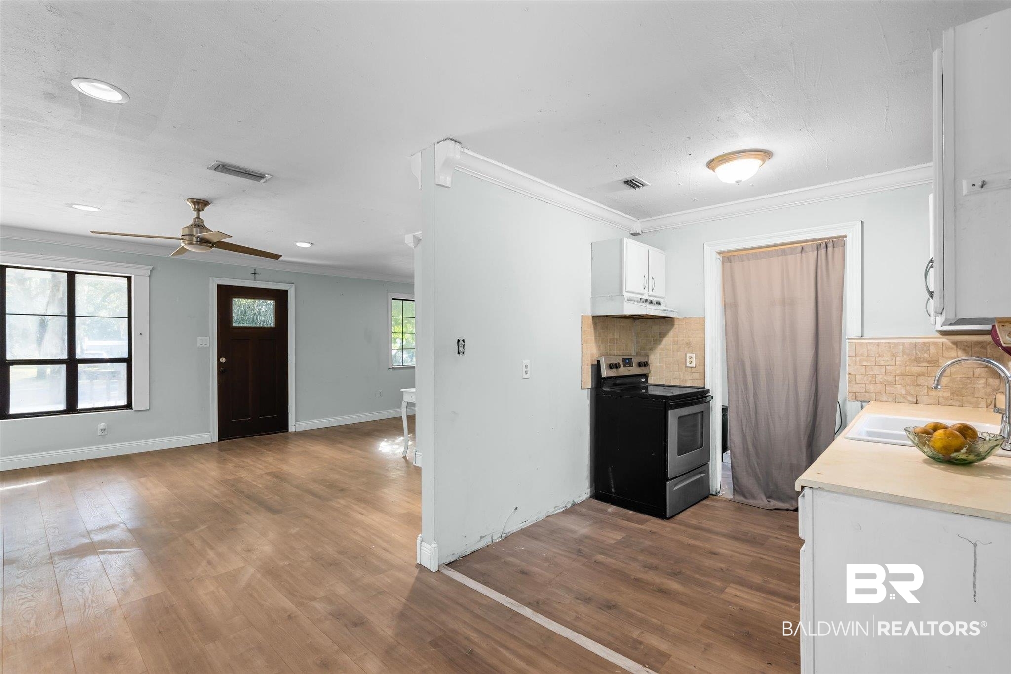 6233 Ponder Road Fairhope, AL 36532 - Photo 7 of 20 Kitchen with stainless steel electric stove, a healthy amount of sunlight, white cabinetry, and sink