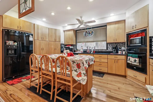 a kitchen with stainless steel appliances kitchen island granite countertop a refrigerator a stove a sink and dishwasher with wooden floor