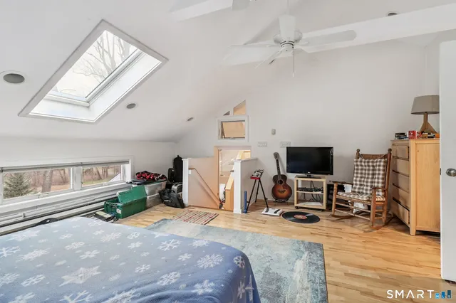 a bedroom with a bed a flat screen tv and a window