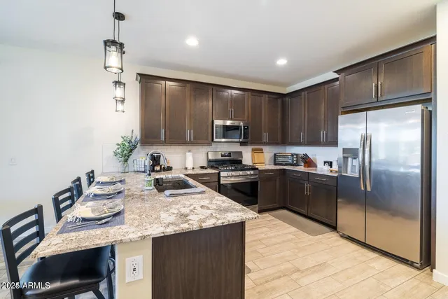 a kitchen with kitchen island granite countertop a refrigerator stove top oven and sink