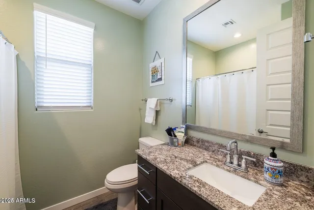 a bathroom with a granite countertop sink toilet and mirror
