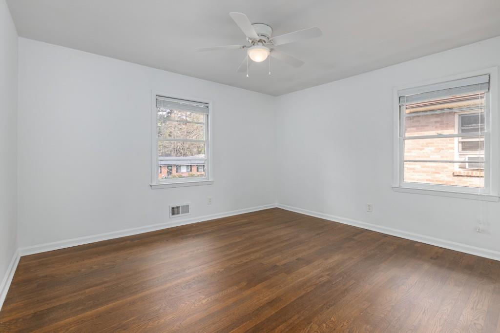 282 Willis Mill Road Southwest Atlanta, GA 30311 - Photo 14 of 25 an empty room with wooden floor ceiling fan and windows