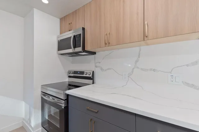 a kitchen with granite countertop white cabinets and stainless steel appliances
