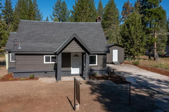 a front view of house with yard and trees in the background