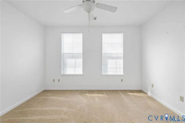 an empty room with windows and chandelier fan