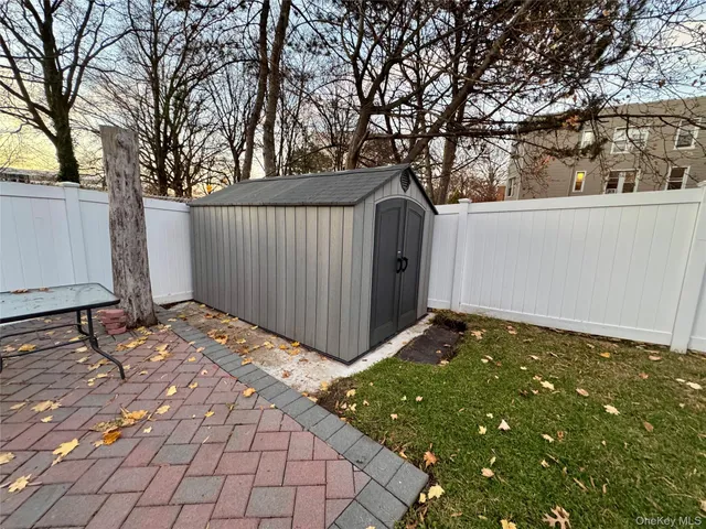 a backyard of a house with large trees and wooden fence