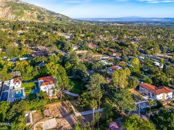 an aerial view of residential houses with outdoor space and trees