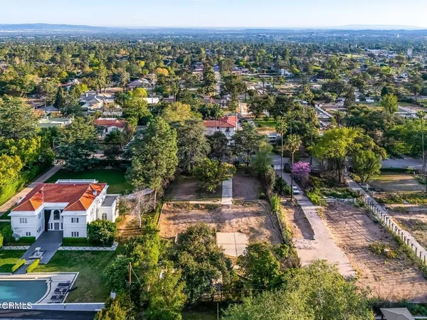 an aerial view of residential houses with outdoor space and trees
