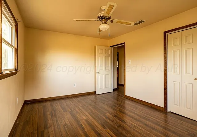 a view of an empty room with wooden floor and window