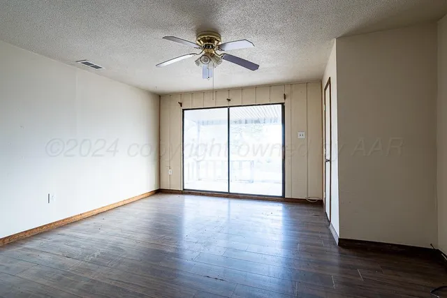a view of empty room with wooden floor and fan