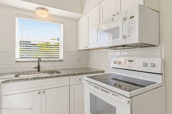 a kitchen with granite countertop a sink a stove and cabinets