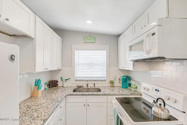a kitchen with granite countertop a sink a stove and cabinets