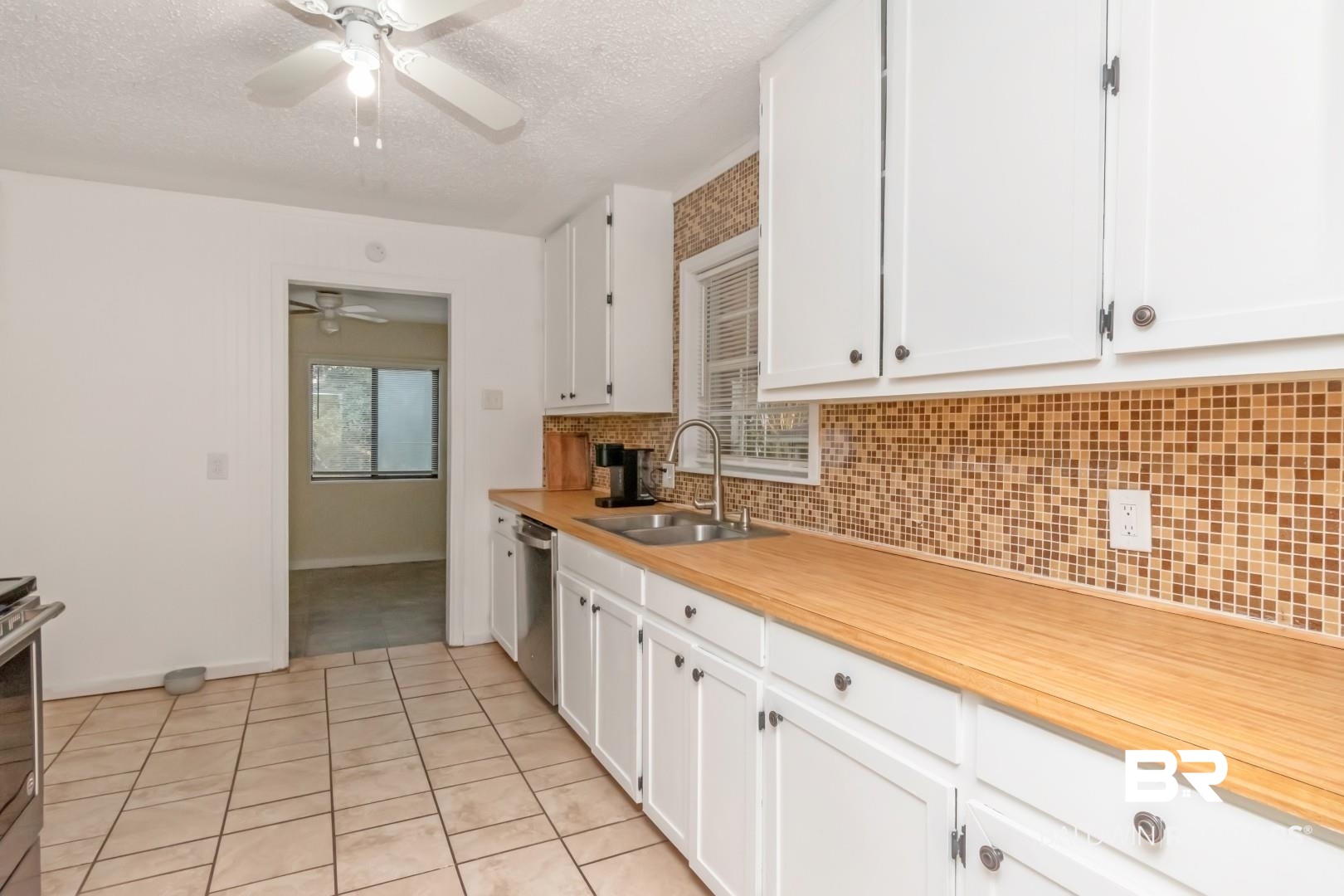 61 Nack Lane Mobile, AL 36608 - Photo 4 of 25 Kitchen with sink, white cabinetry, a textured ceiling, stainless steel dishwasher, and backsplash