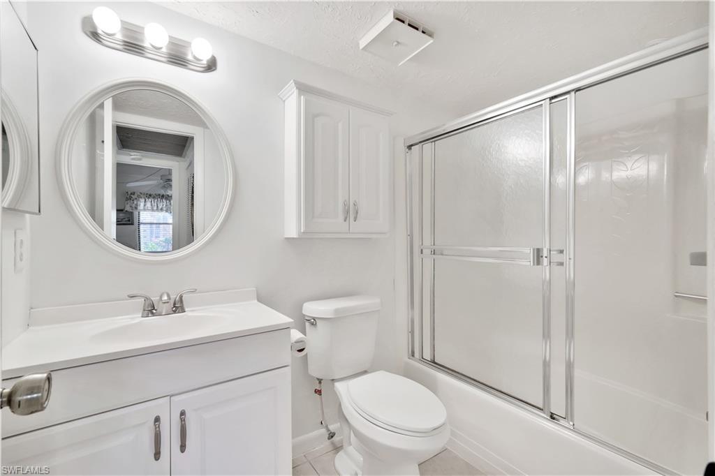4357 27th Court Southwest, Unit 101 Naples, FL 34116 - Photo 17 of 25 a bathroom with a toilet a sink a vanity and mirror