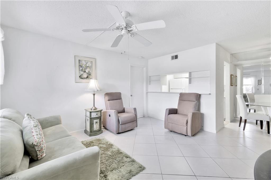 4357 27th Court Southwest, Unit 101 Naples, FL 34116 - Photo 6 of 25 a living room with furniture and a chandelier