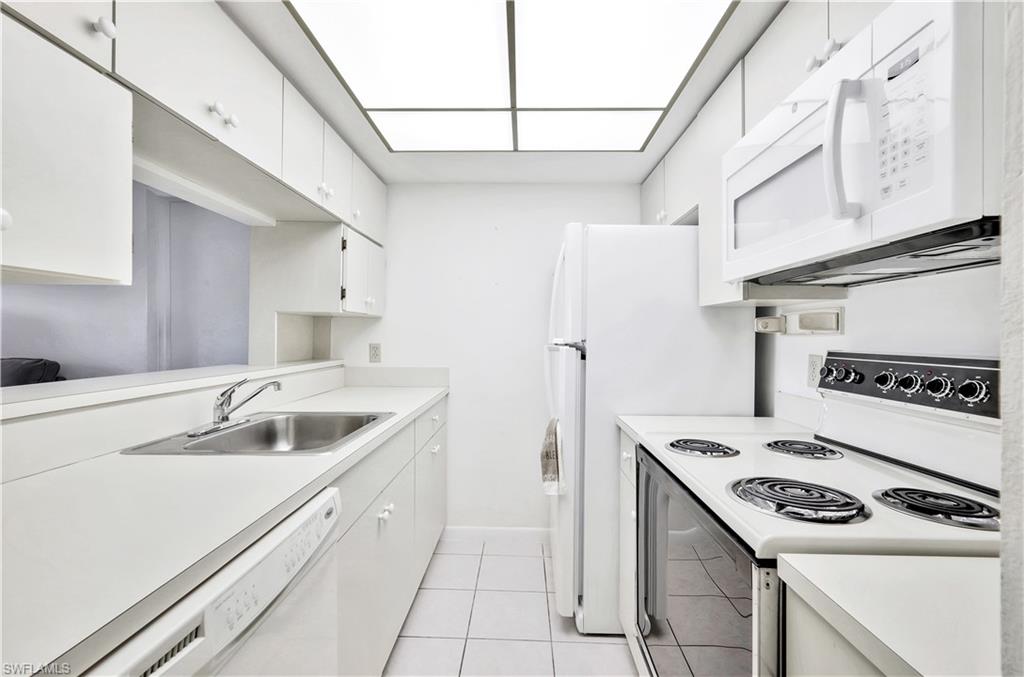 4357 27th Court Southwest, Unit 101 Naples, FL 34116 - Photo 7 of 25 a kitchen that has a sink a stove and a refrigerator