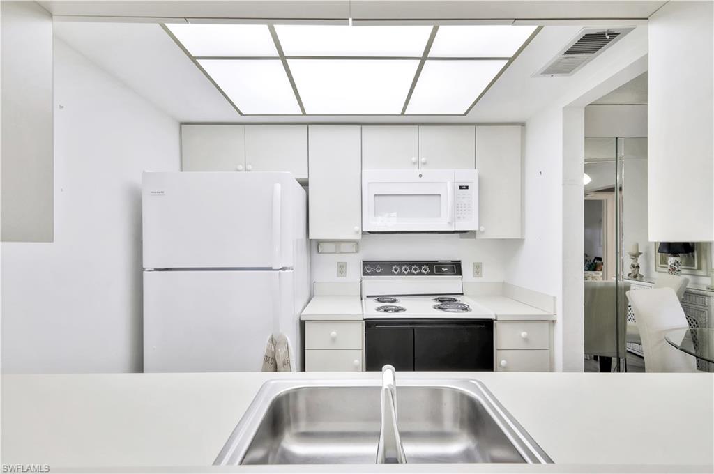 4357 27th Court Southwest, Unit 101 Naples, FL 34116 - Photo 9 of 25 a kitchen with a sink a refrigerator and a stove