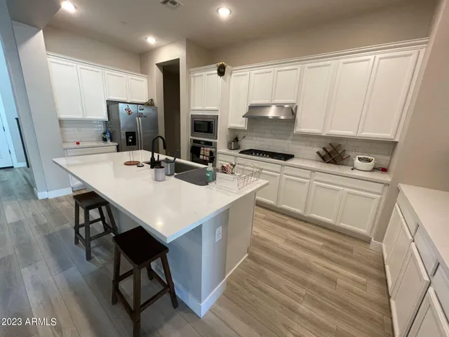 a kitchen with a sink a stove a refrigerator and white cabinets