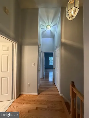 an empty room with wooden floor mirror and windows
