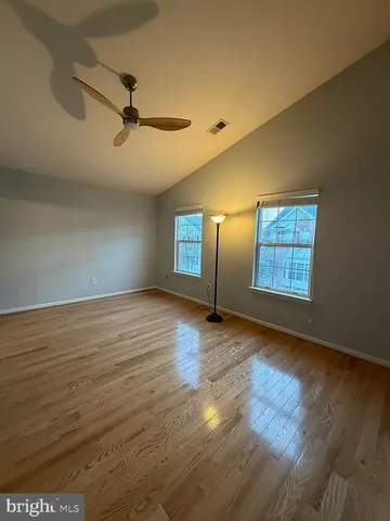 a view of an empty room with window and wooden floor