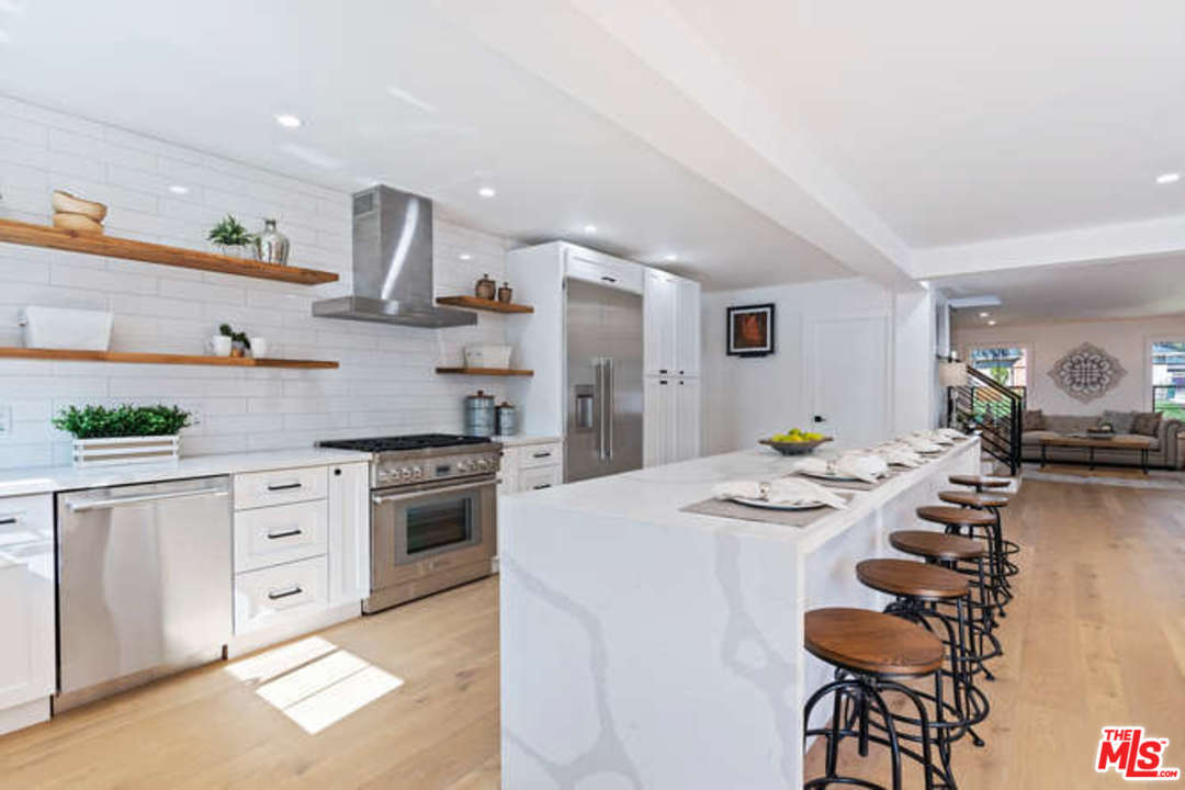 3628 Grayburn Road Pasadena, CA 91107 - Photo 8 of 25 a kitchen with stainless steel appliances kitchen island granite countertop a table chairs stove and white cabinets