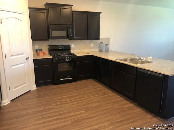 a kitchen with granite countertop a sink cabinets and stainless steel appliances