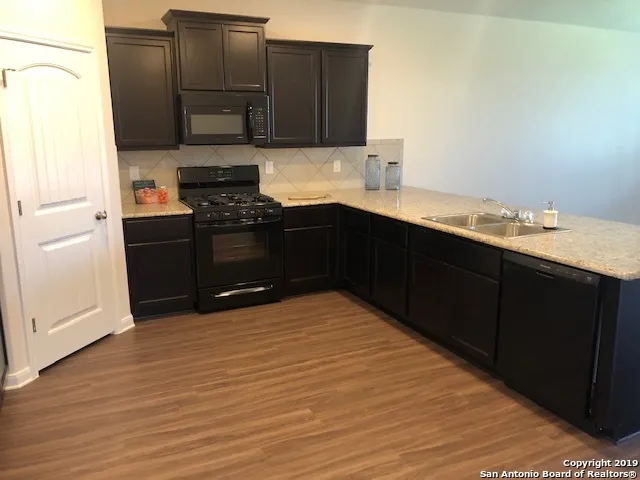 a kitchen with granite countertop a sink cabinets and stainless steel appliances