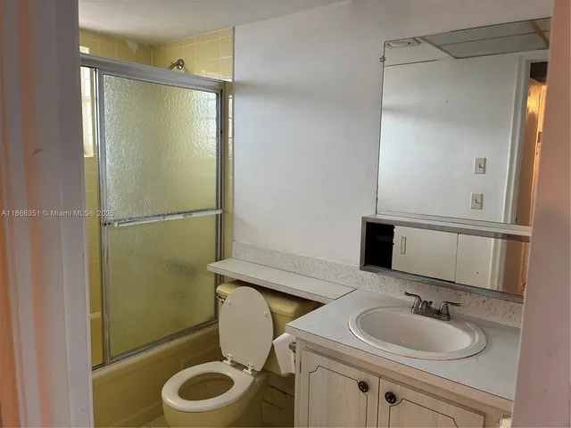 a bathroom with a granite countertop sink toilet and a mirror