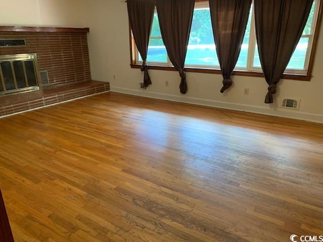 48 Sandpiper Lane, Unit 48 SANDPIPER LANE Georgetown, SC 29440 - Photo 4 of 10 Unfurnished living room featuring light wood-style floors and a fireplace