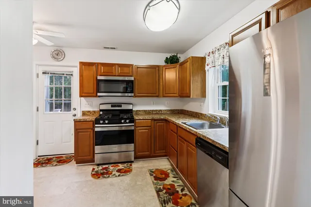 a view of a livingroom with furniture a kitchen wooden floor and window