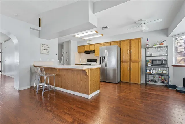 a kitchen with stainless steel appliances granite countertop a refrigerator a stove and a wooden floors