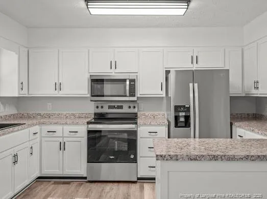 a kitchen with granite countertop white cabinets and stainless steel appliances