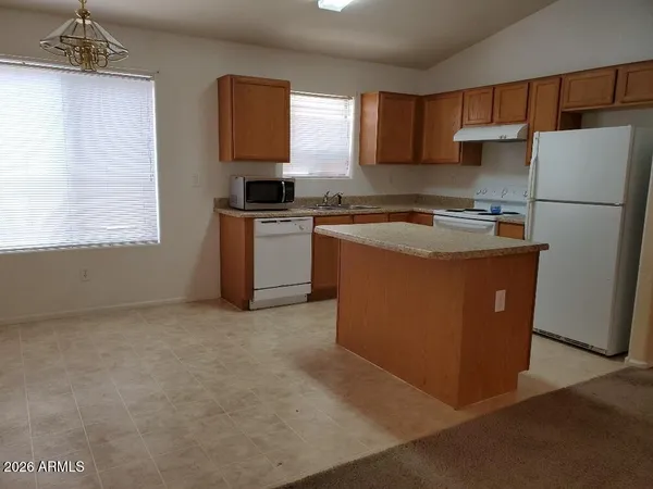 a kitchen with stainless steel appliances granite countertop a refrigerator a sink dishwasher a stove a microwave oven and a dining table with wooden floor