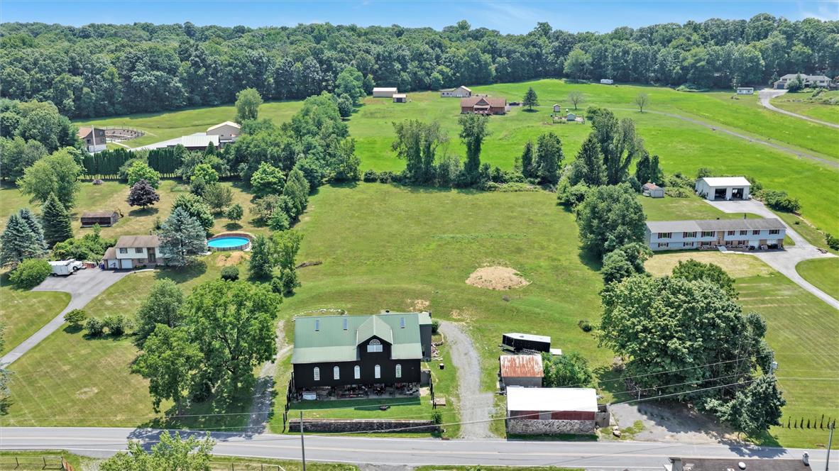 101 Conrad Road Fleetwood, PA 19522 - Photo 35 of 42 An aerial perspective reveals a rural landscape with various homes and outbuildings nestled amongst verdant trees and open fields.