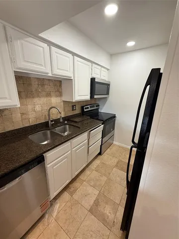 a kitchen with granite countertop a sink a stove and a microwave